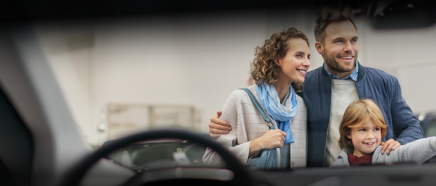 A family standing in front of a car