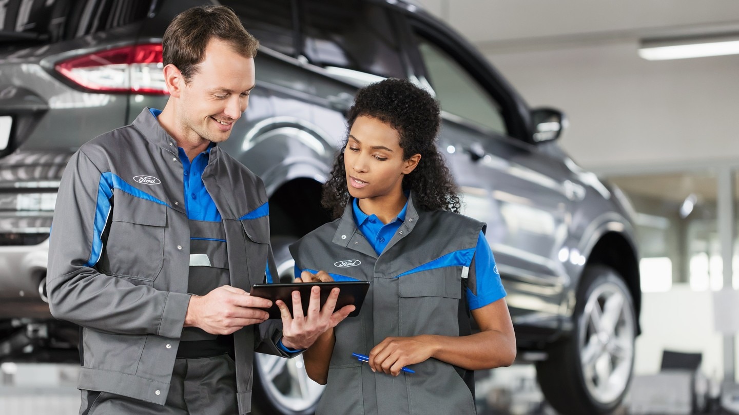 Two technicians working on a tablet in a Ford workshop